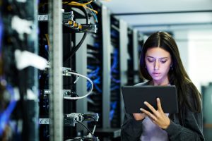 Female technician using digital tablet examining in server room